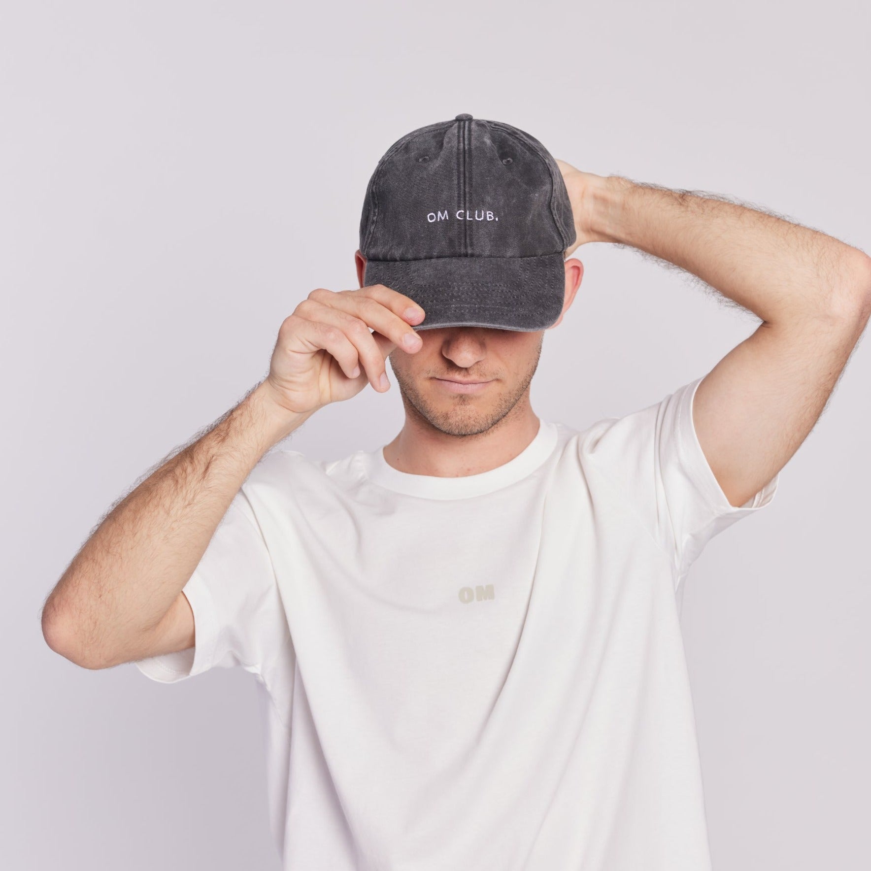 schwarze kappe mit stick "om club." von person getragen