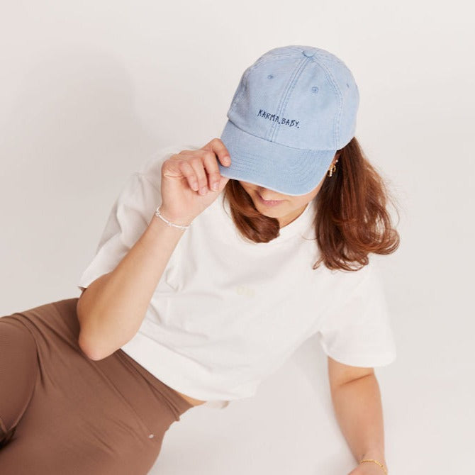 hellblaue kappe mit stick "karma,baby." von person getragen