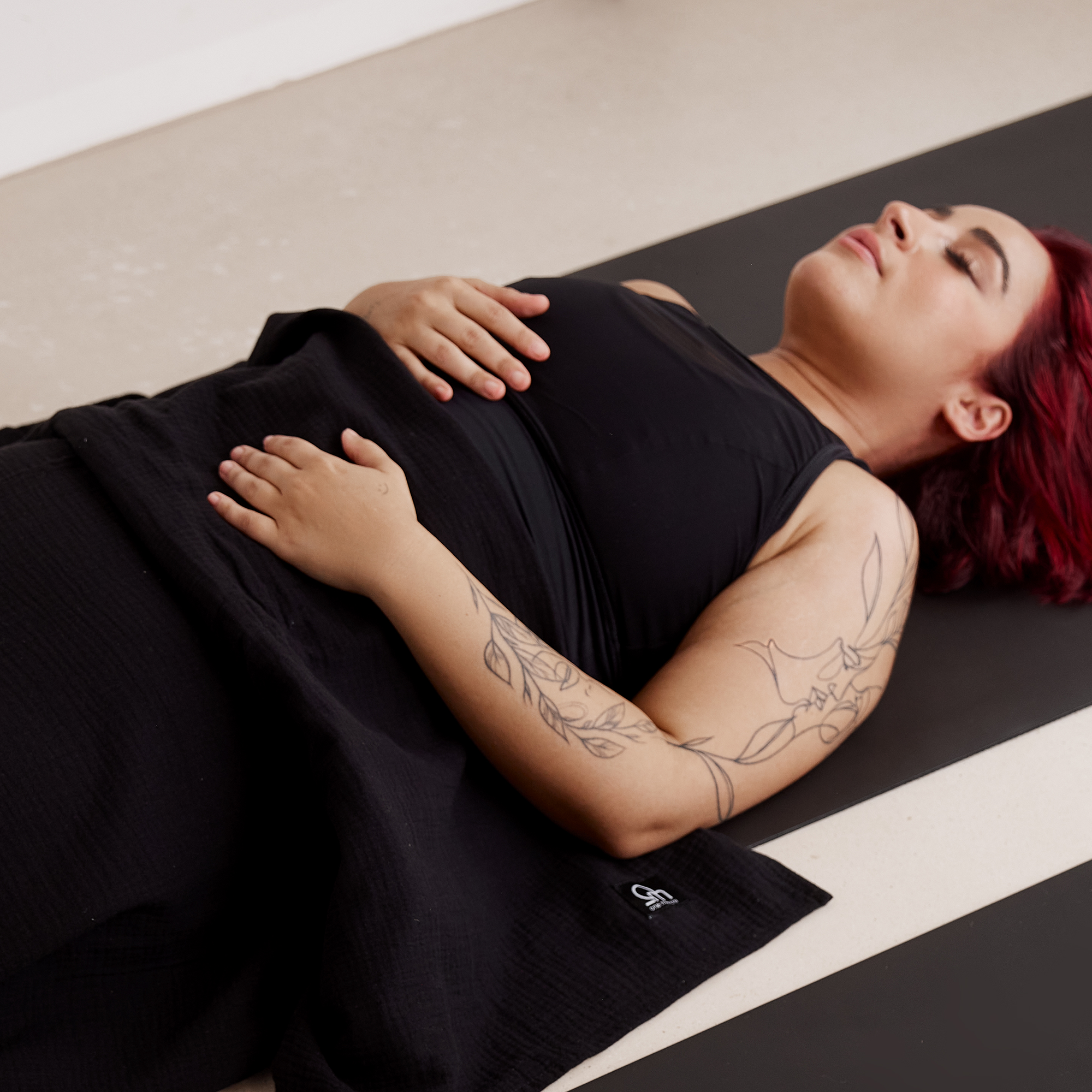 Person mit Yogadecke auf schwarzer Yogamatte